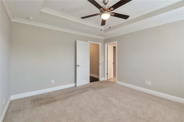 carpeted spare room with a tray ceiling, ornamental molding, and ceiling fan