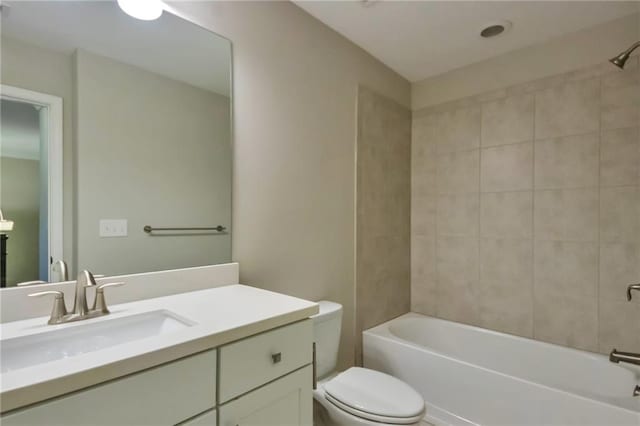 full bathroom featuring vanity, tiled shower / bath, and toilet