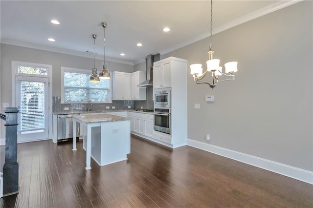 kitchen featuring pendant lighting, stainless steel appliances, a kitchen island, and wall chimney range hood