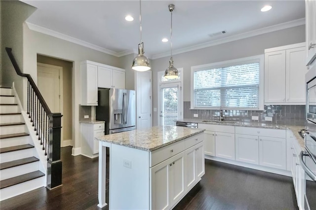 kitchen with sink, white cabinetry, light stone counters, appliances with stainless steel finishes, and a kitchen island