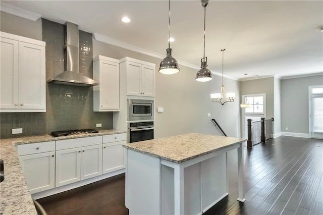 kitchen featuring light stone countertops, appliances with stainless steel finishes, wall chimney range hood, and white cabinets