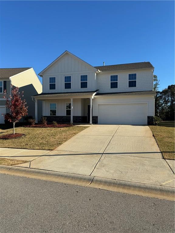 136 Paulownia Cir, Mcdonough, GA 30253 - modern farmhouse with a garage, concrete driveway, board and batten siding, stone siding, and a front yard