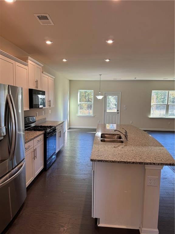 136 Paulownia Cir, Mcdonough, GA 30253 - kitchen featuring appliances with stainless steel finishes, dark wood-type flooring, light stone countertops, recessed lighting, and a center island with sink