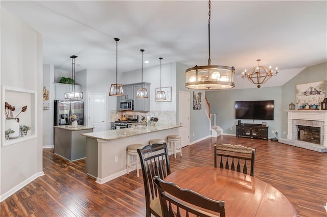 dining room with vaulted ceiling, dark hardwood / wood-style flooring, and a brick fireplace