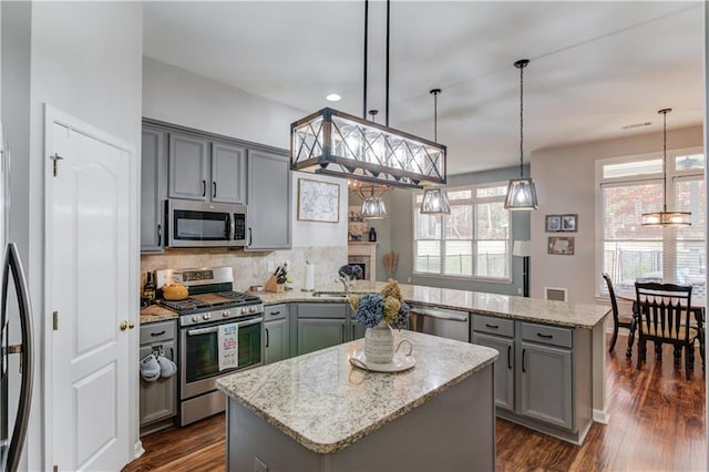 kitchen with dark wood-type flooring, a center island, pendant lighting, and appliances with stainless steel finishes