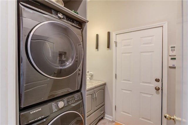 laundry area featuring cabinets, light tile patterned floors, and stacked washer and dryer