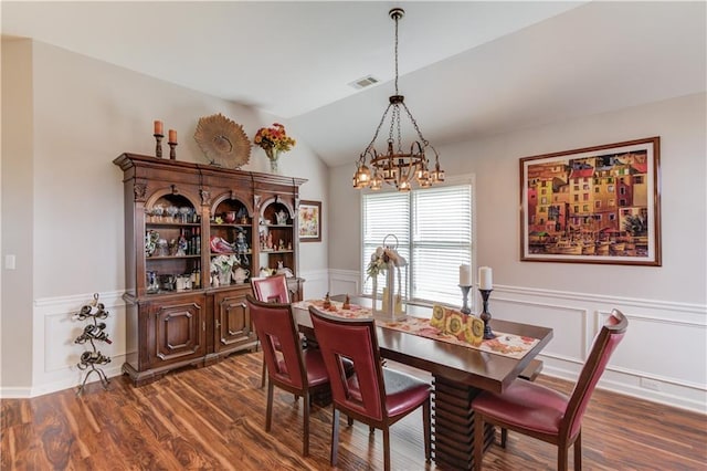 dining area with dark wood-type flooring, vaulted ceiling, and a notable chandelier