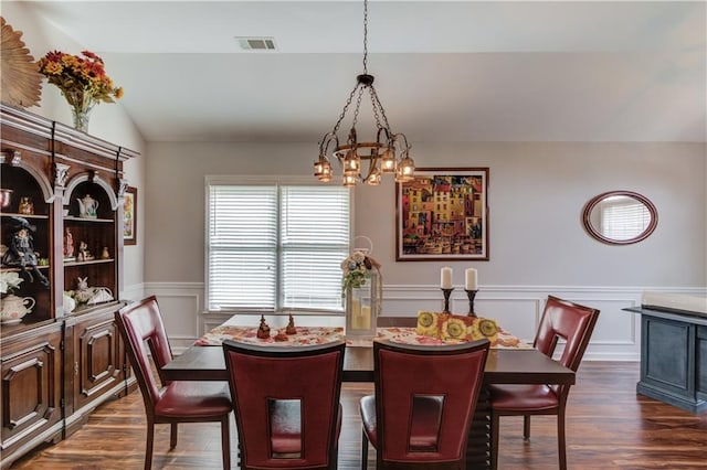 dining space featuring lofted ceiling, dark wood-type flooring, and a notable chandelier