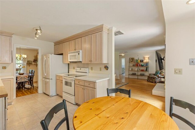 kitchen with white appliances, light countertops, light brown cabinets, and light wood-style floors
