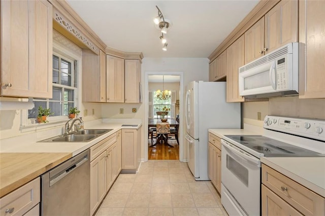 kitchen with white appliances, a sink, light countertops, a chandelier, and plenty of natural light