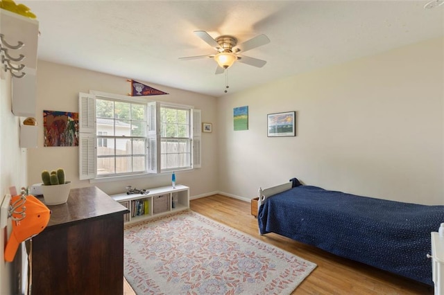 bedroom with light wood-style flooring, ceiling fan, and baseboards