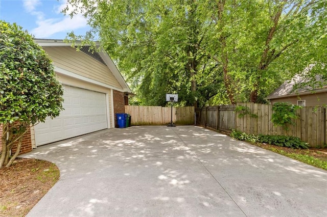 garage with concrete driveway and fence