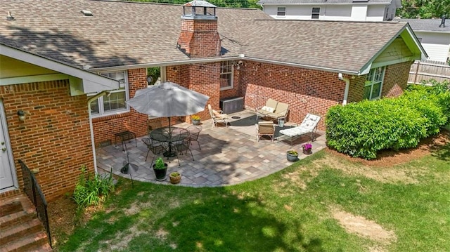 rear view of house featuring brick siding, a chimney, and a patio
