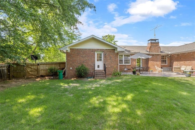 back of property with entry steps, brick siding, a patio, and a gate