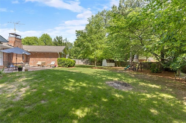 view of yard with a playground, a storage shed, a patio area, and an outbuilding