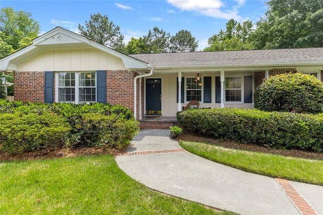 ranch-style home with brick siding, a porch, and a front yard