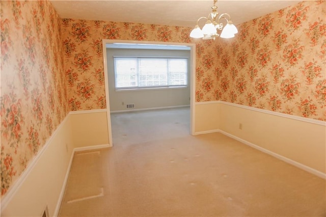 carpeted empty room featuring a chandelier