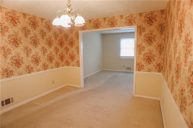 carpeted spare room with an inviting chandelier