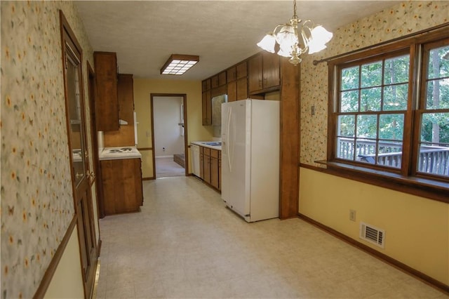 kitchen featuring white refrigerator with ice dispenser, a chandelier, and hanging light fixtures