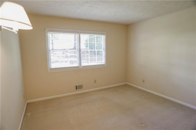 carpeted empty room featuring a textured ceiling