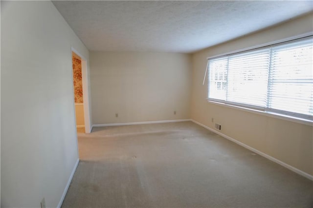 empty room with a textured ceiling and light colored carpet