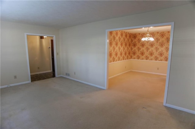 carpeted empty room featuring a chandelier