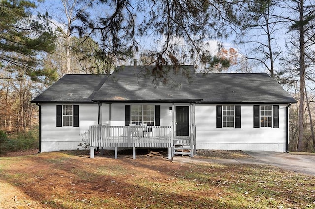 ranch-style house featuring roof with shingles and a wooden deck