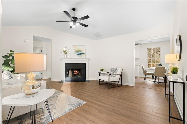 living area featuring lofted ceiling, wood finished floors, and visible vents