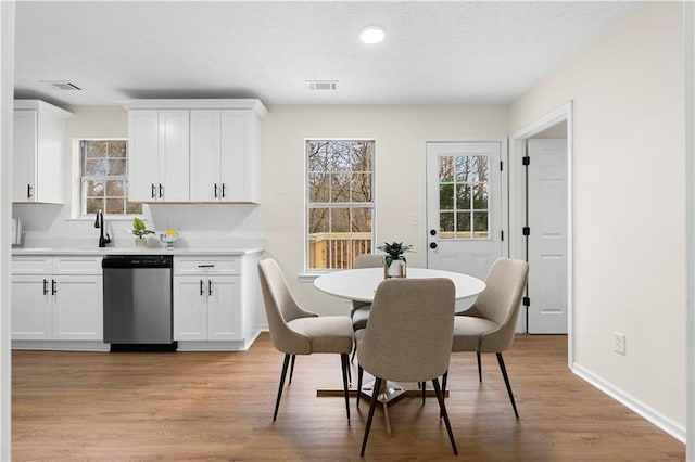dining room featuring light wood-type flooring, a healthy amount of sunlight, and visible vents