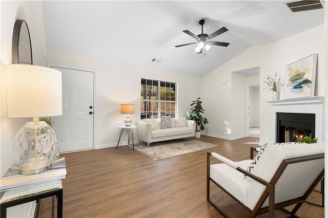 living area with baseboards, lofted ceiling, and visible vents