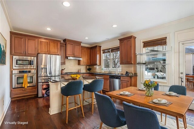 kitchen featuring stainless steel appliances, ornamental molding, dark hardwood / wood-style floors, and decorative backsplash