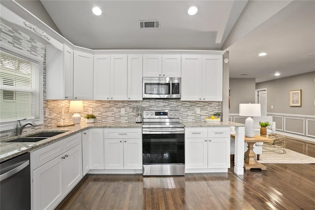 1684 Braeburn Dr SE, Atlanta, GA 30316 - kitchen with appliances with stainless steel finishes, a sink, white cabinets, dark wood-style flooring, and vaulted ceiling