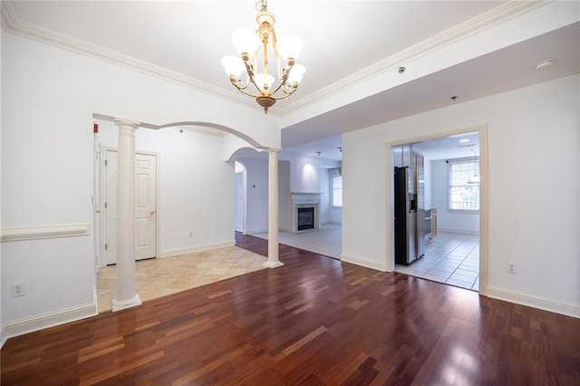 spare room featuring a glass covered fireplace, decorative columns, and light wood-style floors