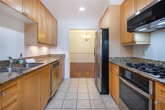 kitchen featuring light stone countertops, pendant lighting, stainless steel appliances, and a sink