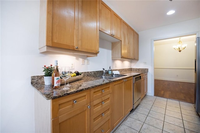 kitchen with light tile patterned flooring, a sink, baseboards, stainless steel dishwasher, and dark stone counters