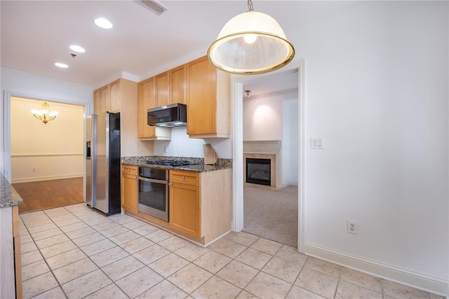 kitchen featuring appliances with stainless steel finishes, dark stone counters, pendant lighting, and visible vents