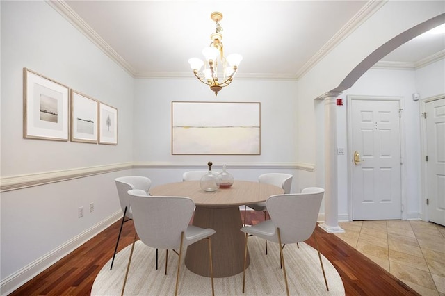 dining area featuring arched walkways, crown molding, ornate columns, and wood finished floors