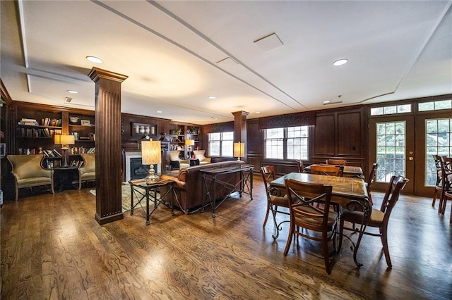 dining area with dark wood-type flooring, a fireplace, and decorative columns