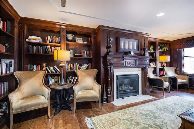 sitting room with wood finished floors, a fireplace with flush hearth, visible vents, and recessed lighting