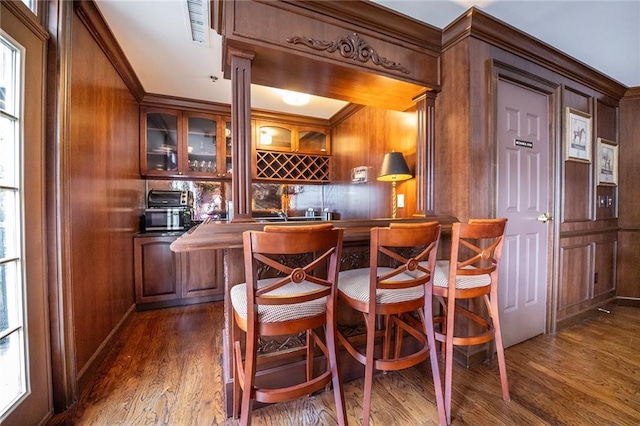 bar featuring wooden walls, visible vents, indoor wet bar, and dark wood-style flooring