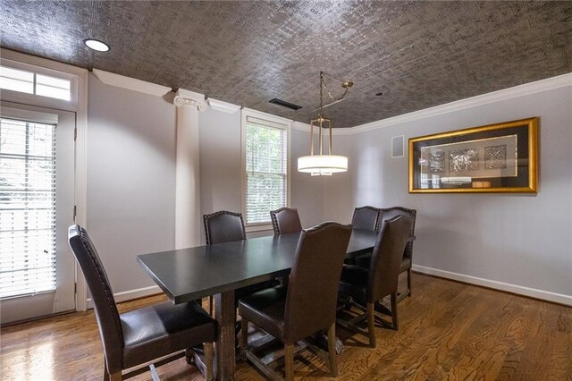 dining space featuring dark wood-style floors, visible vents, crown molding, and baseboards