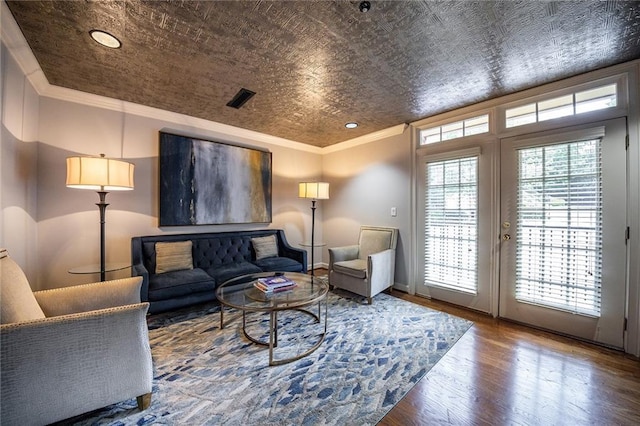 living area featuring ornamental molding, french doors, visible vents, and wood finished floors