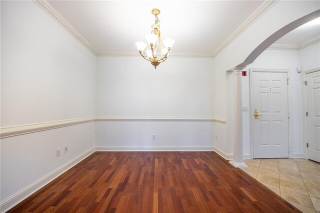 unfurnished dining area with arched walkways, dark wood finished floors, ornate columns, ornamental molding, and baseboards