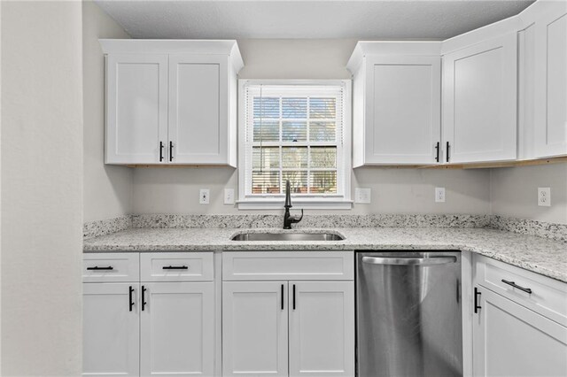 kitchen featuring a sink, light stone counters, stainless steel dishwasher, and white cabinetry