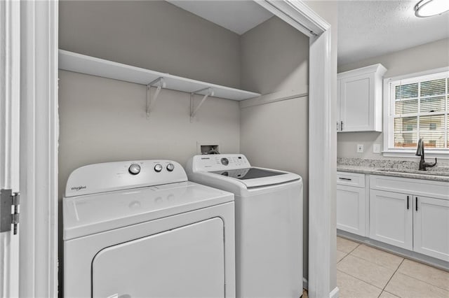 laundry room with light tile patterned floors, independent washer and dryer, a textured ceiling, and a sink