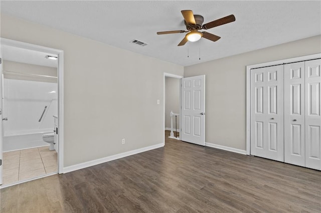 unfurnished bedroom with a closet, visible vents, baseboards, and wood finished floors