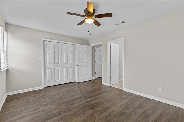 unfurnished bedroom featuring visible vents, baseboards, wood finished floors, a closet, and a textured ceiling