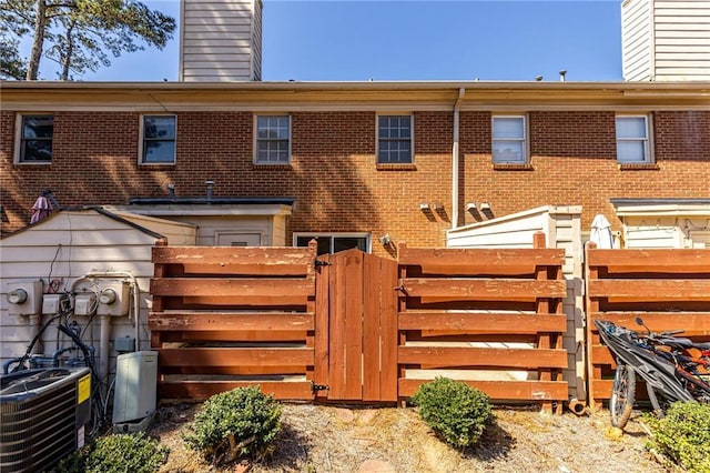 view of gate featuring central AC unit and fence