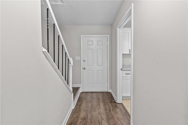 interior space with stairway, a textured ceiling, baseboards, and wood finished floors
