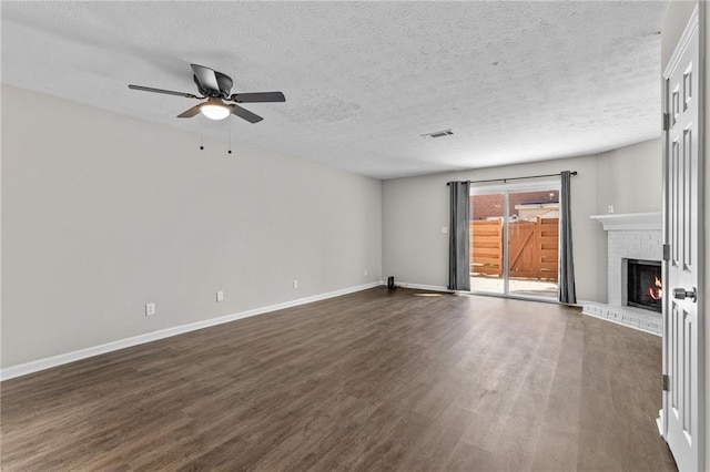 unfurnished living room featuring baseboards, visible vents, a fireplace, dark wood-style flooring, and ceiling fan